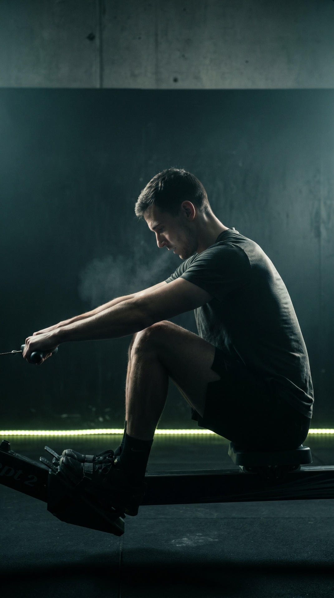 Athlete pulling on the rowing erg in low light.